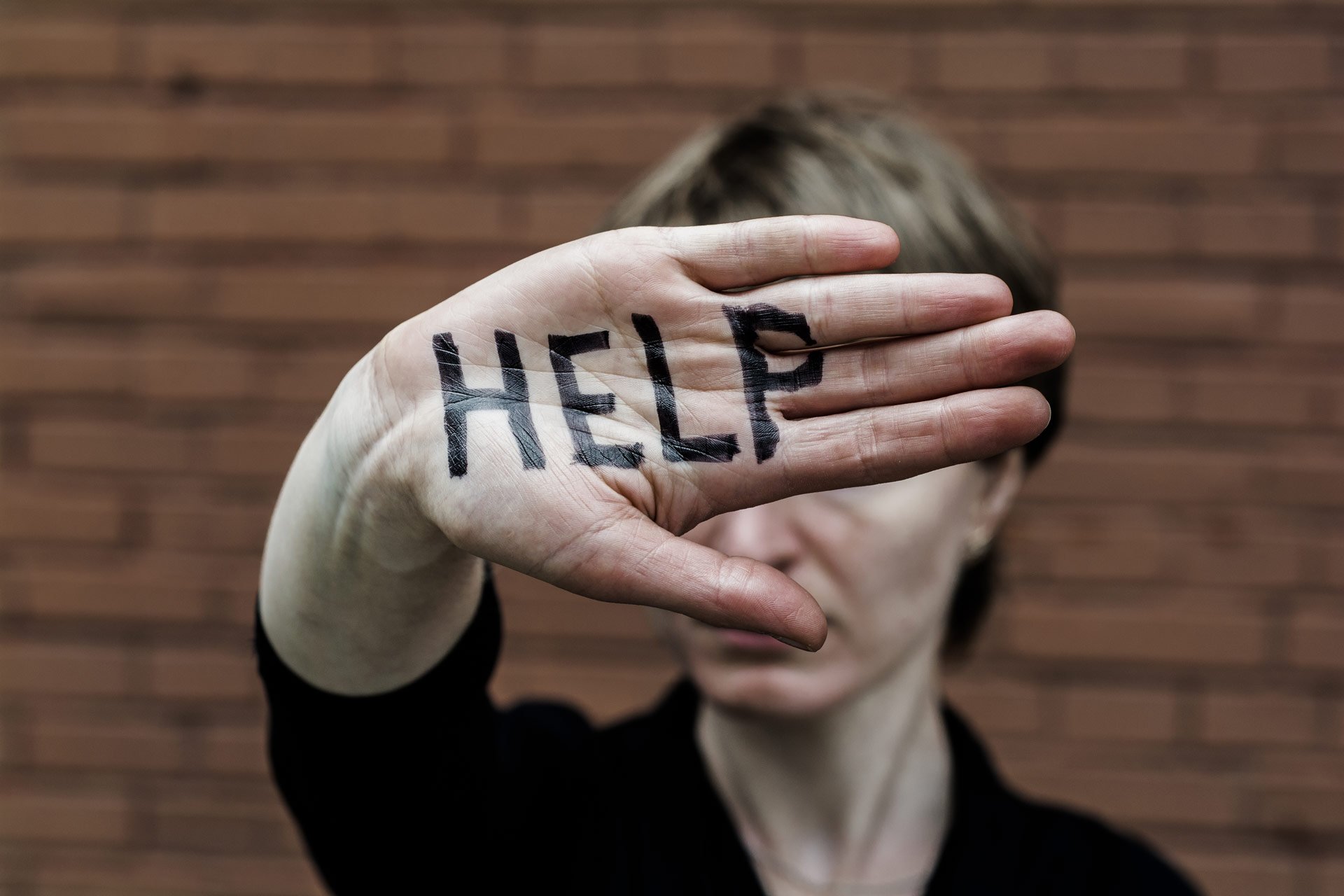 A-woman-covers-her-face-with-his-hand-on-his-hand-written-in-black-marker-'help.jpg